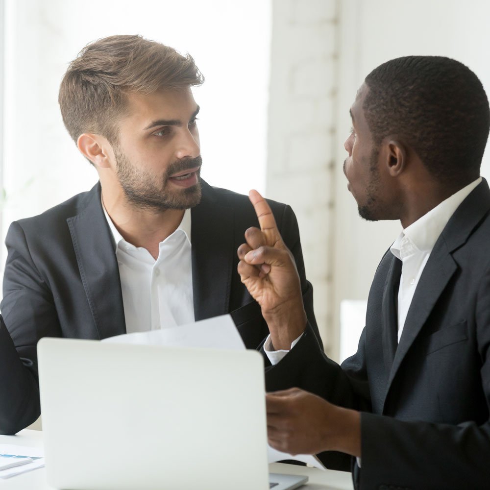 Two professionals discussing emotion regulation in DBT with documents and a laptop in NYC.