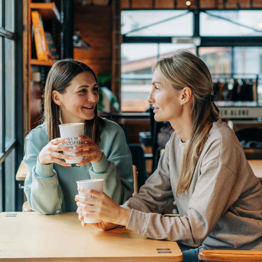 Two women sitting at a café, discussing friendship red flags in NYC - Uncover Counseling.