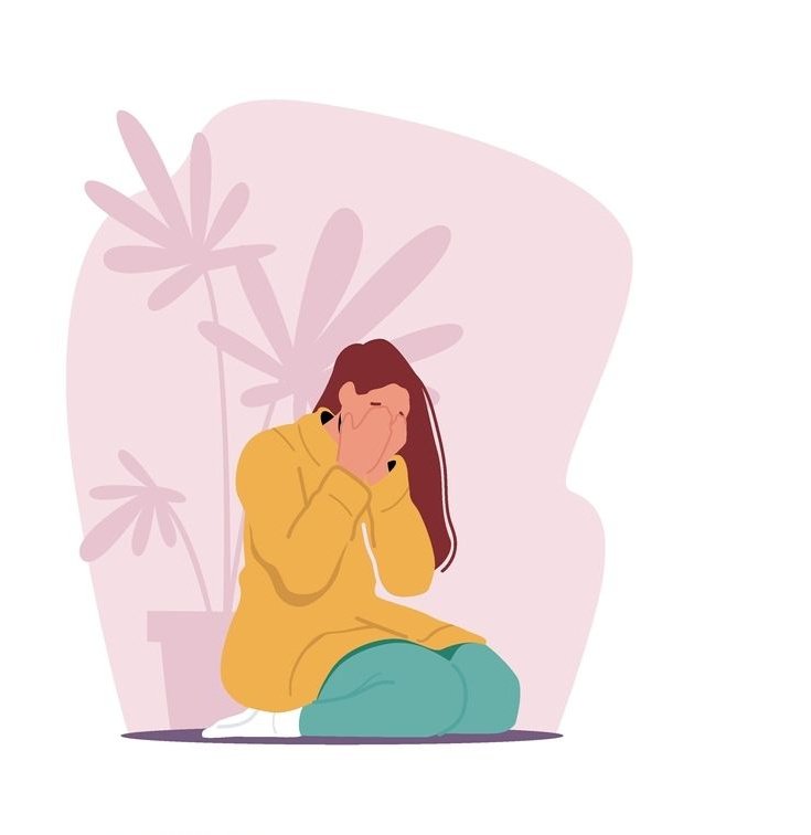 A person sitting on the floor crying in need of Trauma Therapy