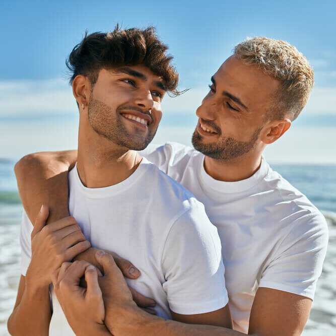 Young boys smiling happy hugging at the beach.