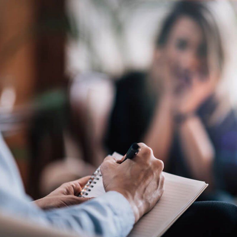 Hands writing in a notebook with a pen, exploring cognitive behavioral therapy benefits in NYC.