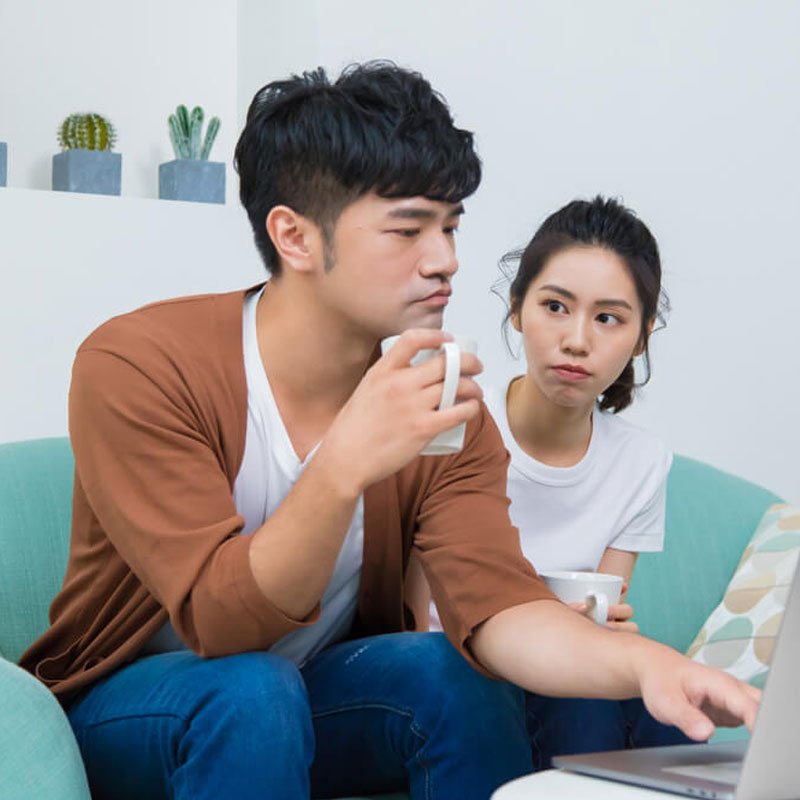 Two people on couch with laptop and mug, stonewalling in a relationship in NYC.