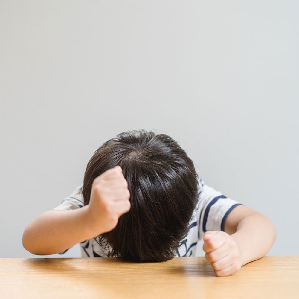 Child with head down and thumbs down, indicating signs of emotional neglect in NYC.