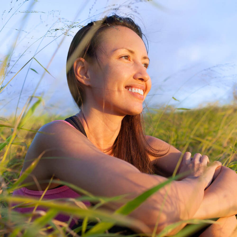 Person sitting in tall grass with a blurred face, reflecting on motivation during depression in NYC.