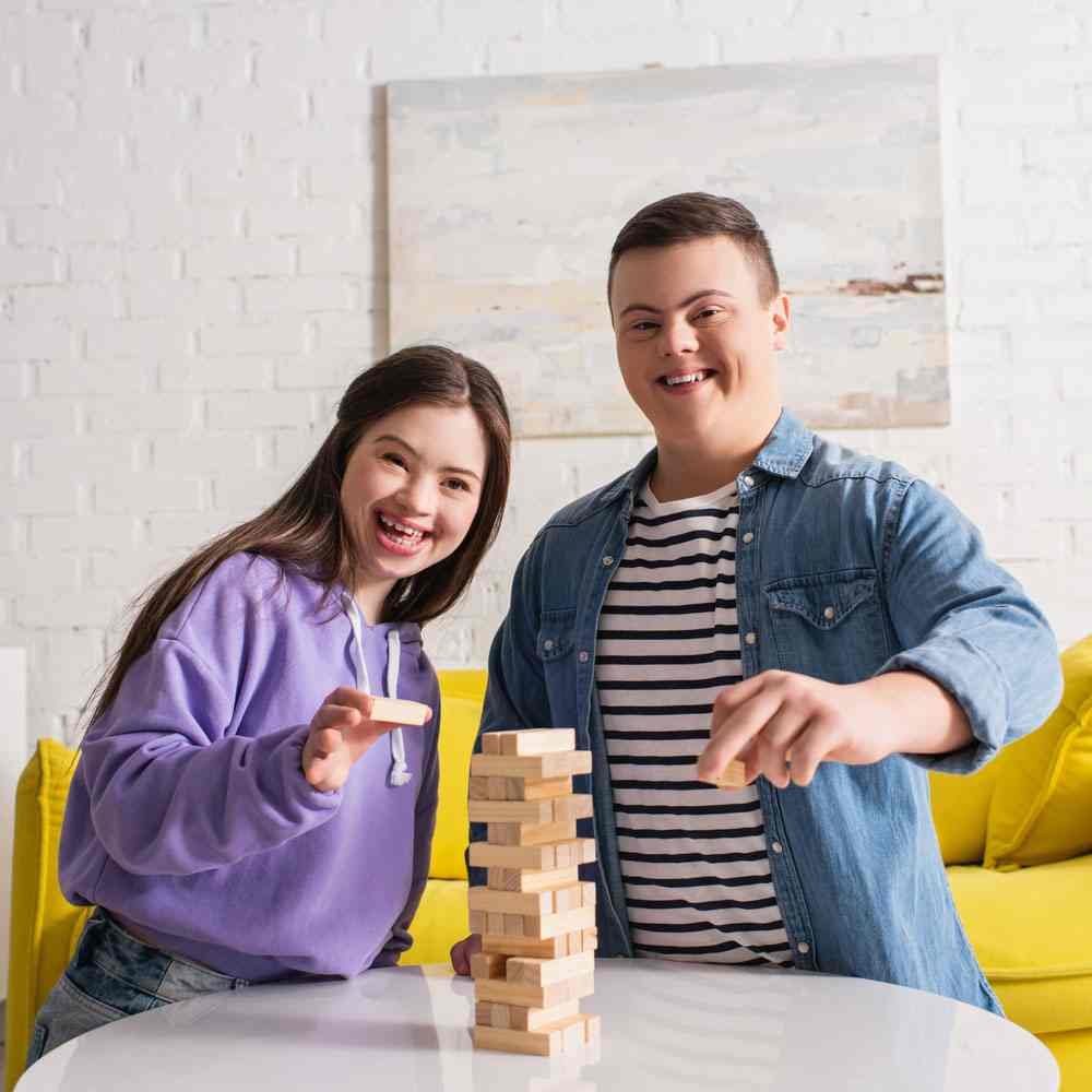 Two people playing Jenga at a table, battling impostor syndrome at work in NYC - Uncover Counseling.