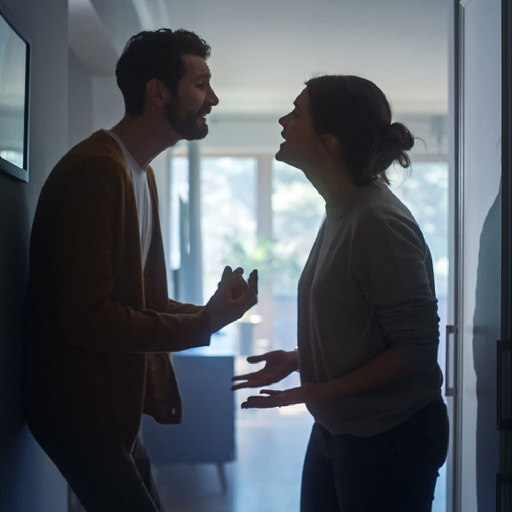 Two people indoors discussing passive-aggressive behavior in relationships - Uncover Counseling NYC.
