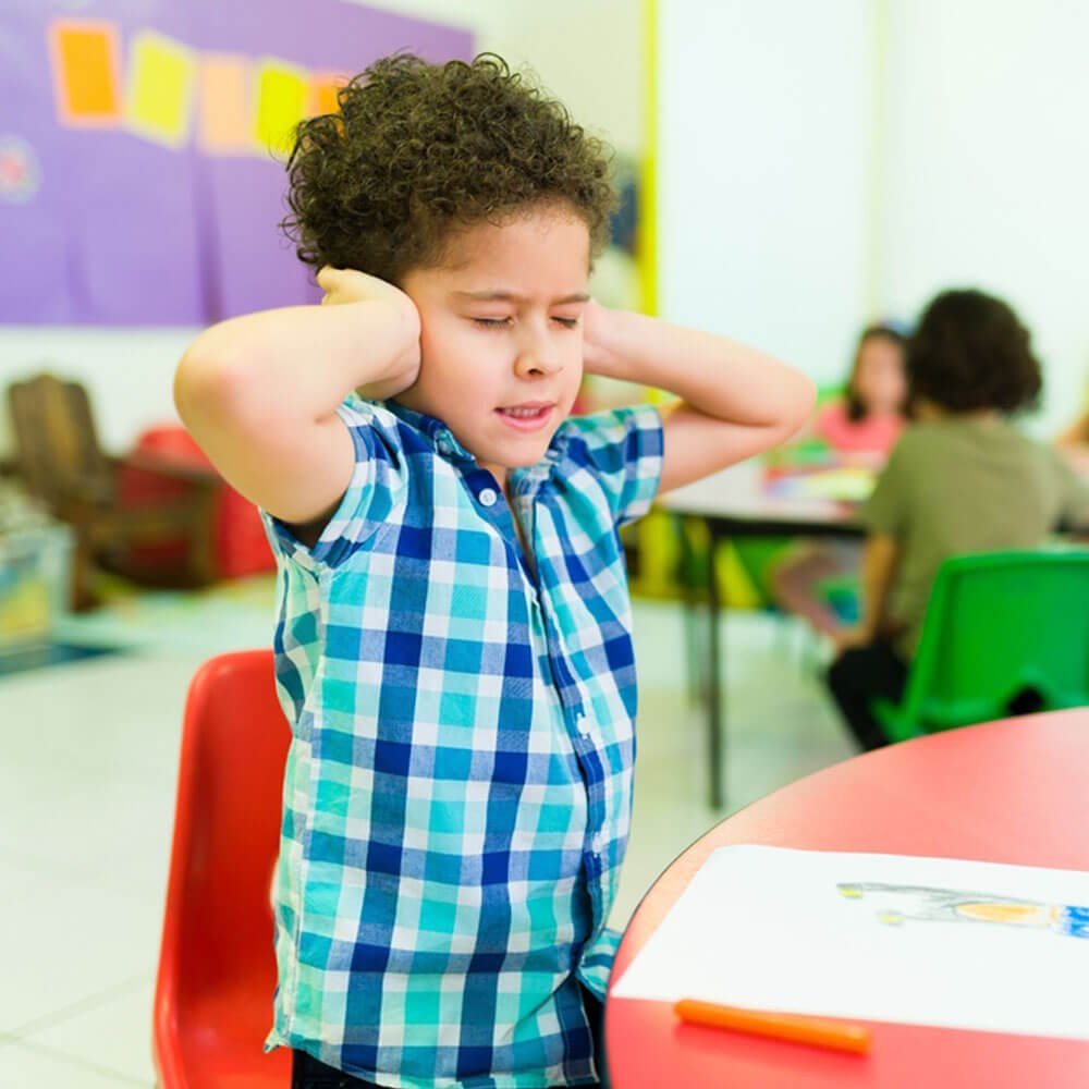 Child in colorful classroom, low-functioning autism signs in NYC.