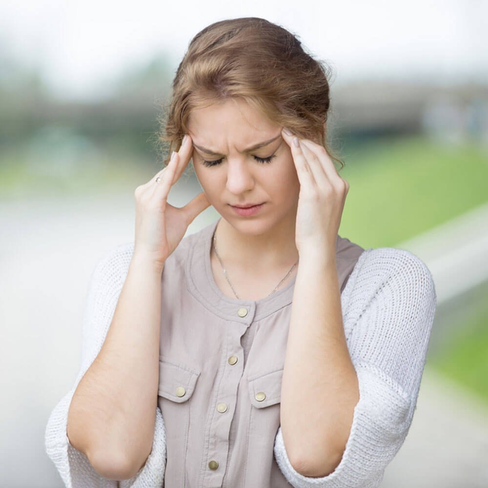Person holding her head, addressing trauma blocking and memory recall in NYC.