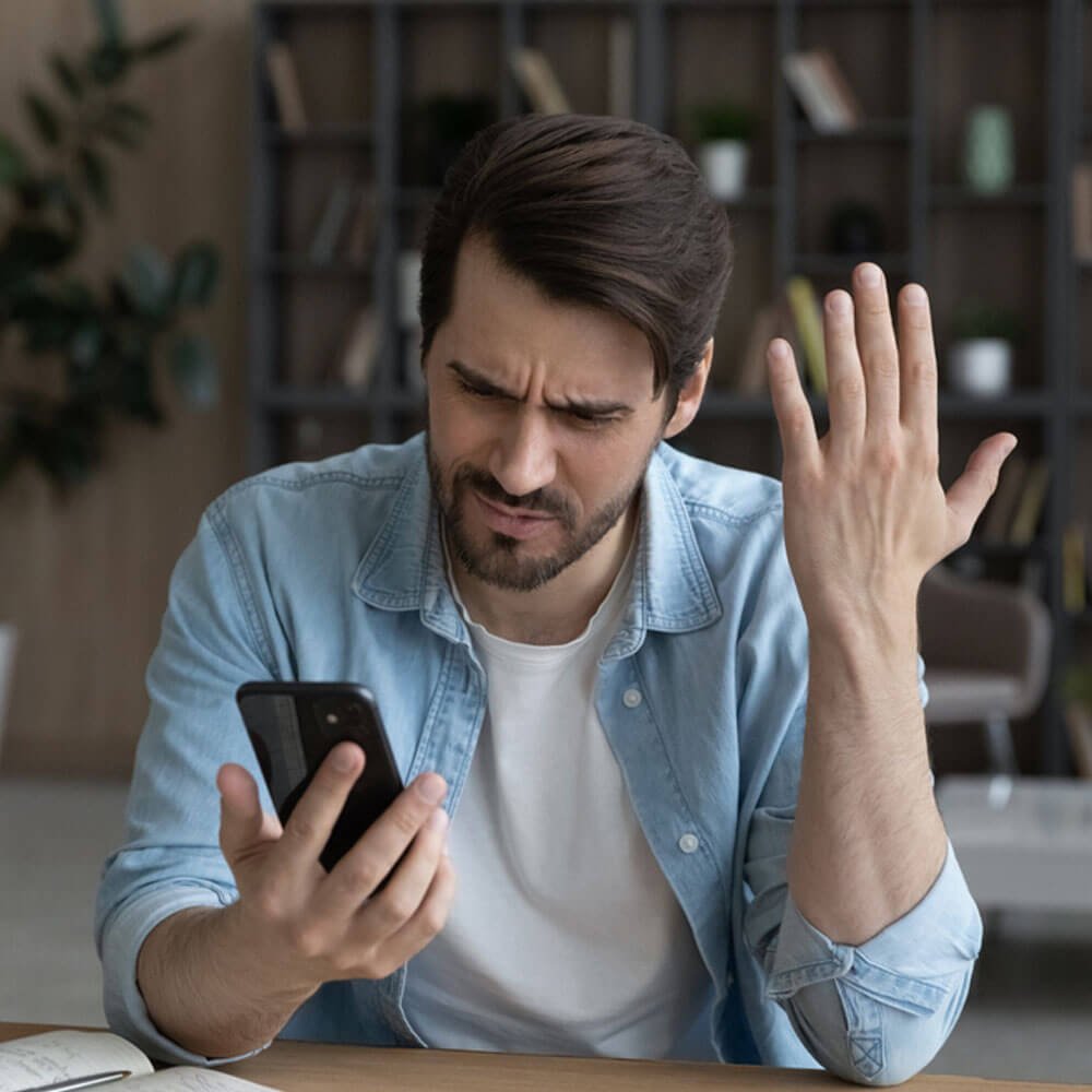 Man holding a smartphone, exploring reasons for constant anger in NYC - Uncover Counseling.