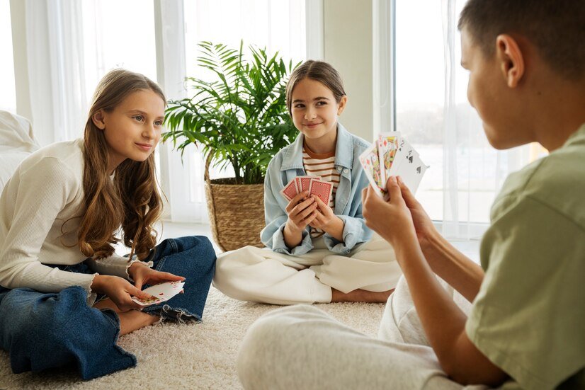 three happy kids playing cards together