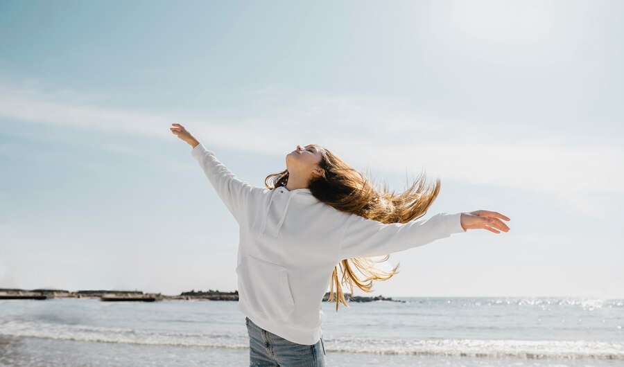keys to a happy life - a young woman enjoying the ocean breeze