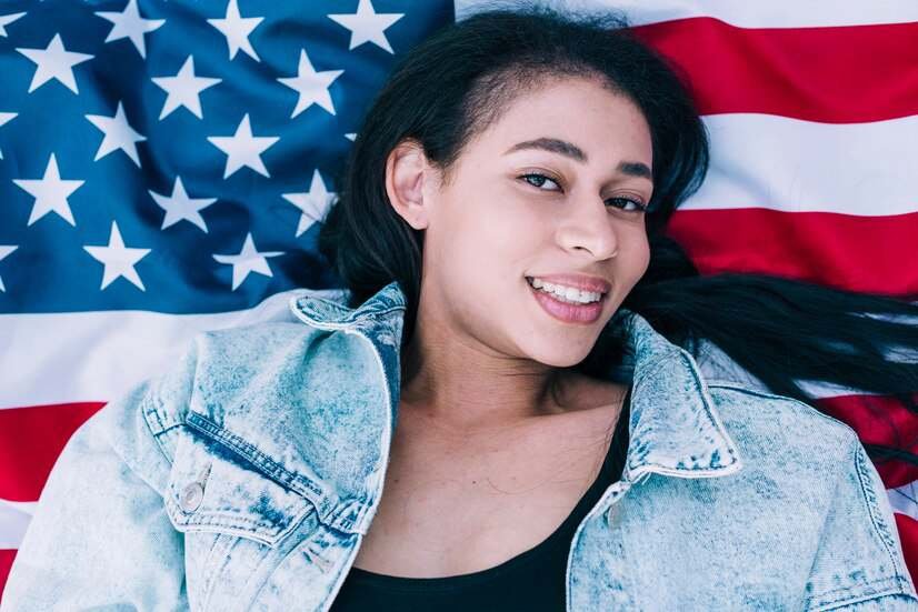 model minority myth - young woman laying on american flag