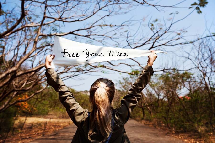 secret to a happy life - a young woman holding a free your mind flag banner