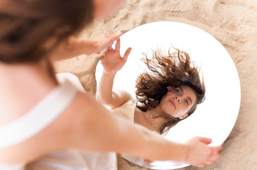 self-awareness - young woman posing confidently outdoors with a round mirror